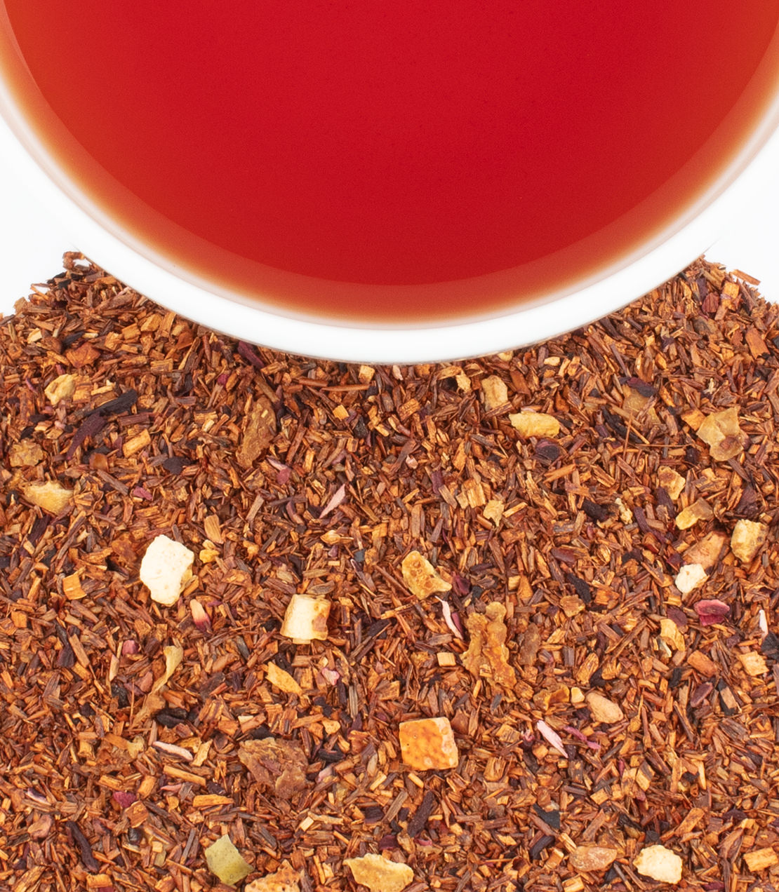 A cup of African Autumn tea above a pile of loose leaf rooibos blend with fruit pieces.