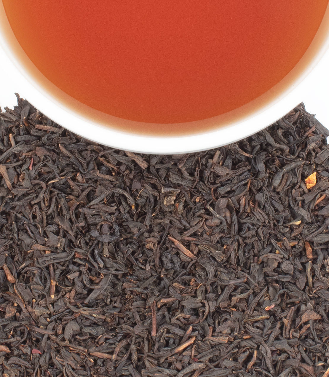Cranberry Autumn tea sachets in a tin, featuring black tea leaves and a warm, brewed cup of tea.