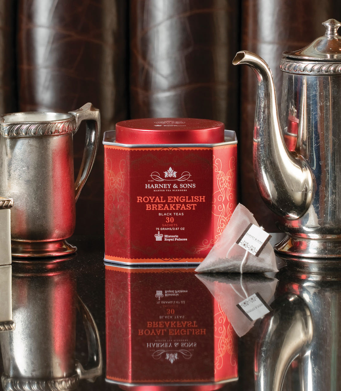 Harney & Sons Royal English Breakfast tea tin with 30 sachets, displayed with silver teapots on a reflective surface.