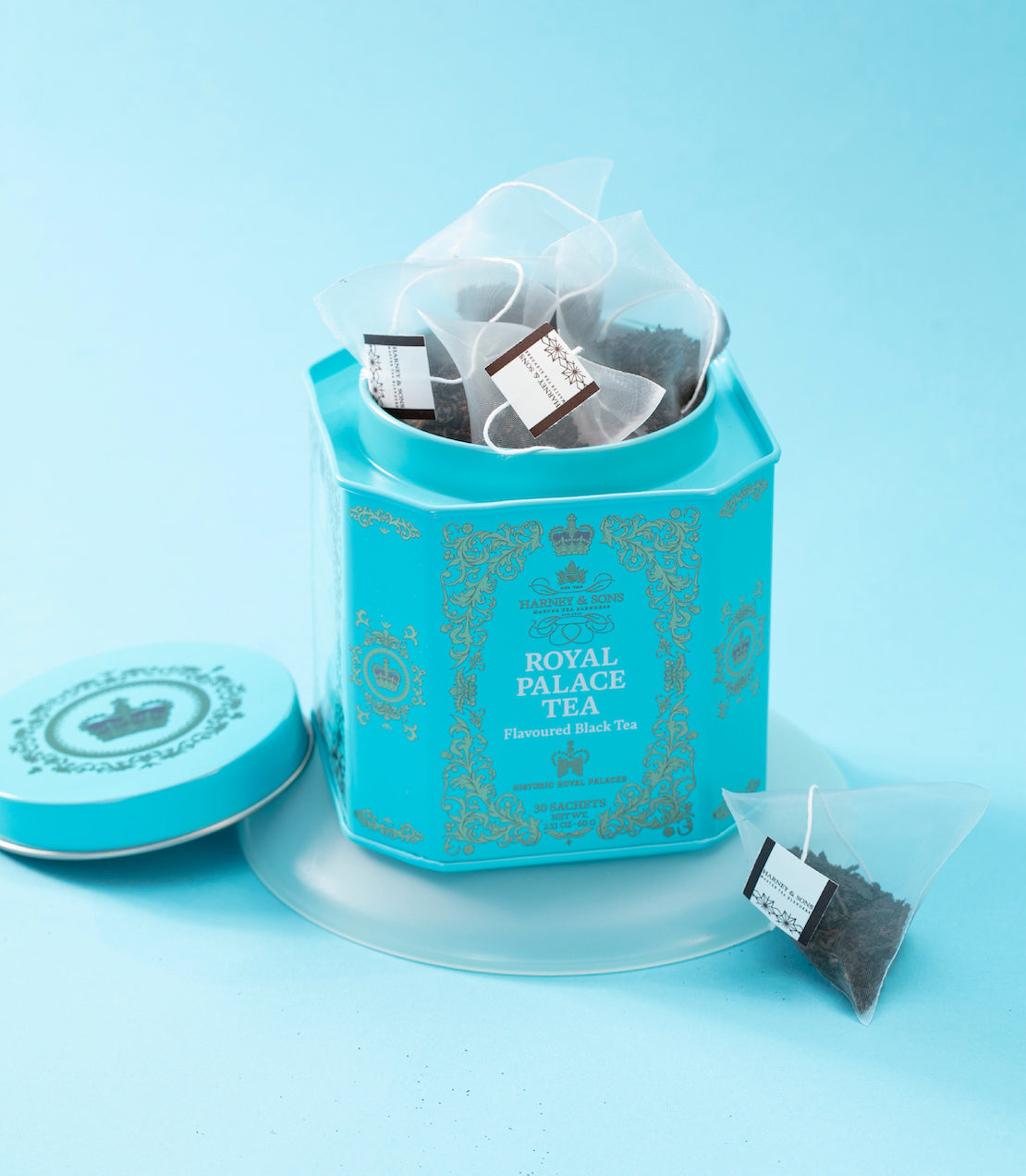 Royal Palace Tea tin with 30 sachets on a silver tray, accompanied by two cups of brewed tea.