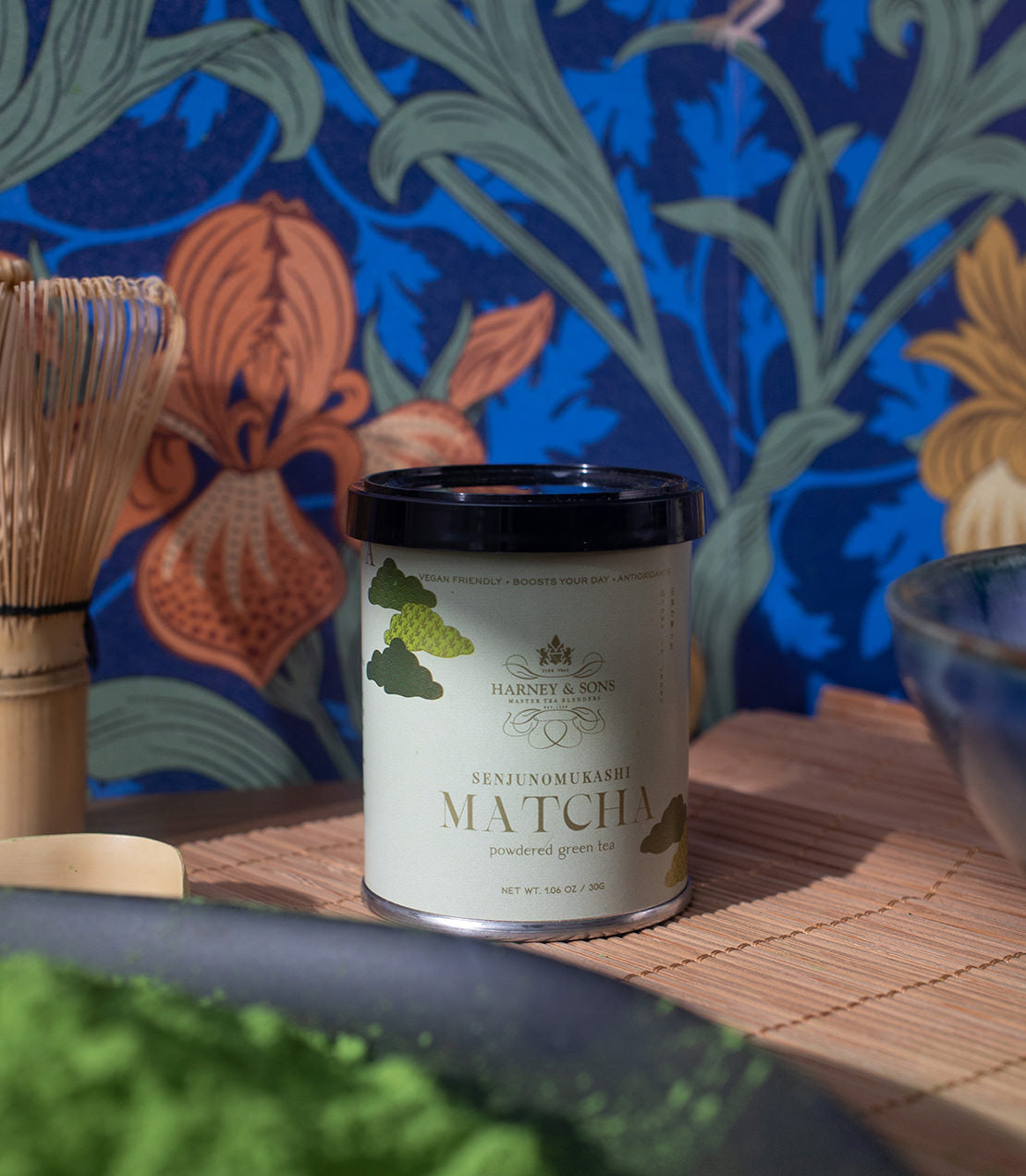 Harney & Sons Senjunomukashi matcha powder canister on a decorative background, showcasing vibrant green tea.