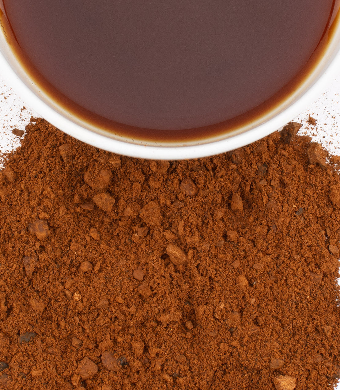 Chaga mushroom powder beside a cup of brewed chaga tea, showcasing its rich brown color and texture.