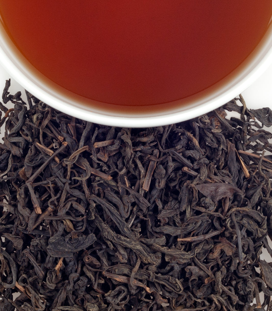 Dark Tibet Tea leaves with a cup of brewed tea, showcasing rich color and texture. Perfect for tea enthusiasts.