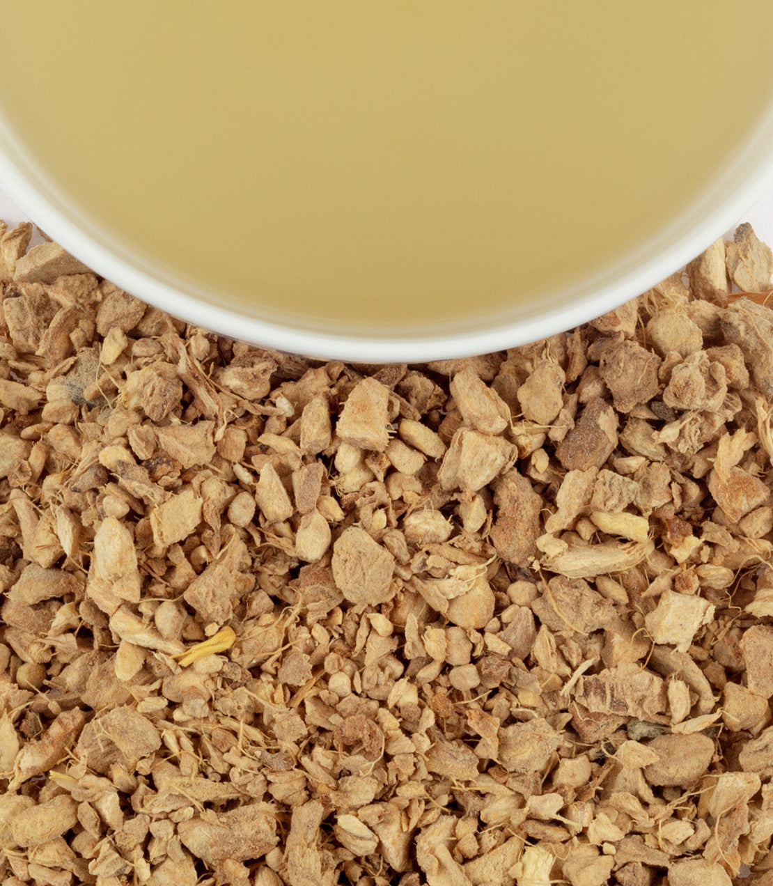 Organic ginger lemon tea sachets in a tin, with dried ginger pieces and a cup of brewed tea.