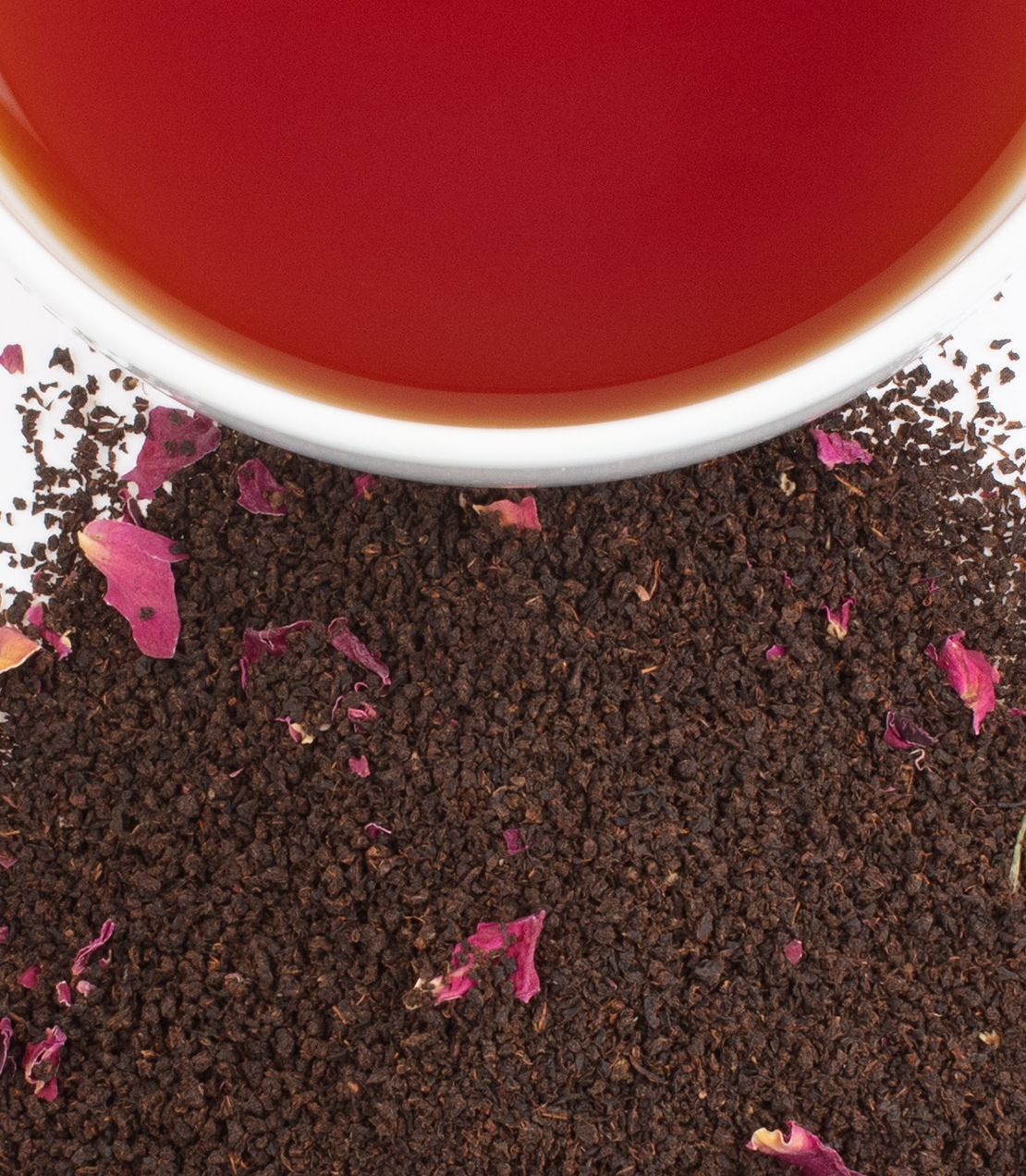 Imperial Windsor Blend tea with loose black tea leaves and rose petals beside a cup of brewed tea.