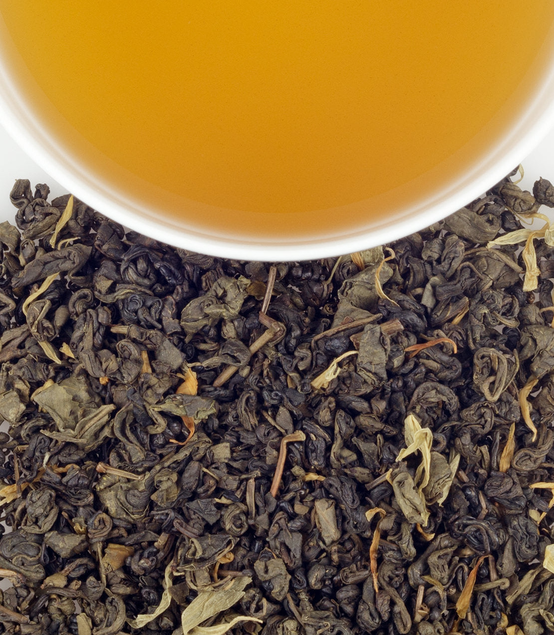 Lemony Gunpowder tea leaves with brewed tea in a cup, showcasing rich color and texture.