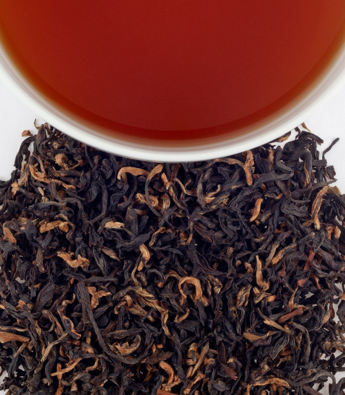 Mokalbari East Full Assam tea leaves with brewed tea in a cup, showcasing rich color and aroma.