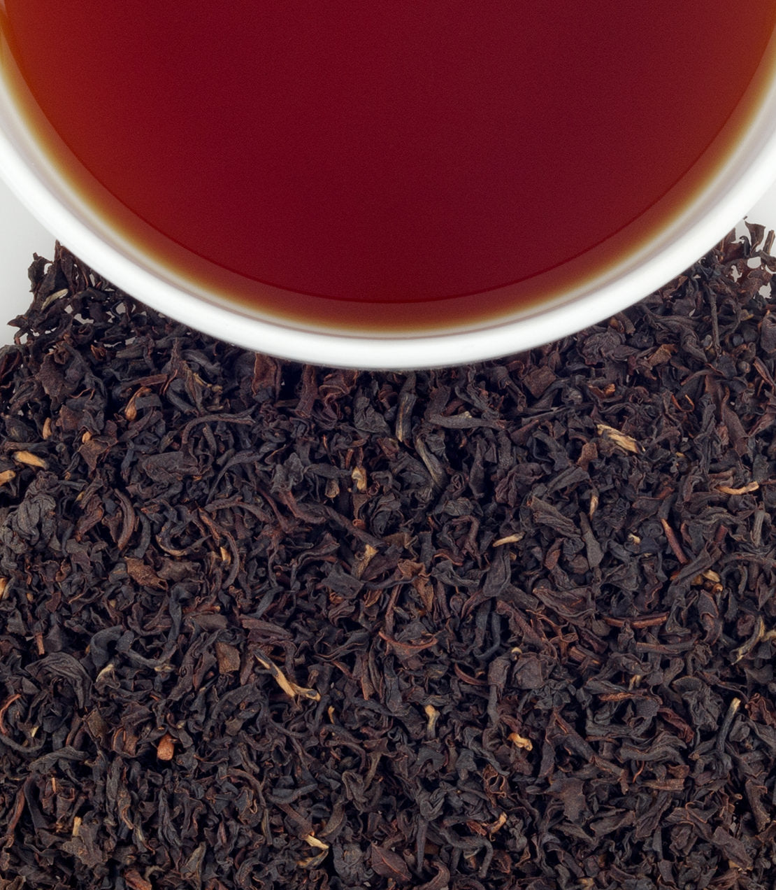 Organic breakfast tea sachets in a bag of 50, with brewed tea in a cup above loose tea leaves.