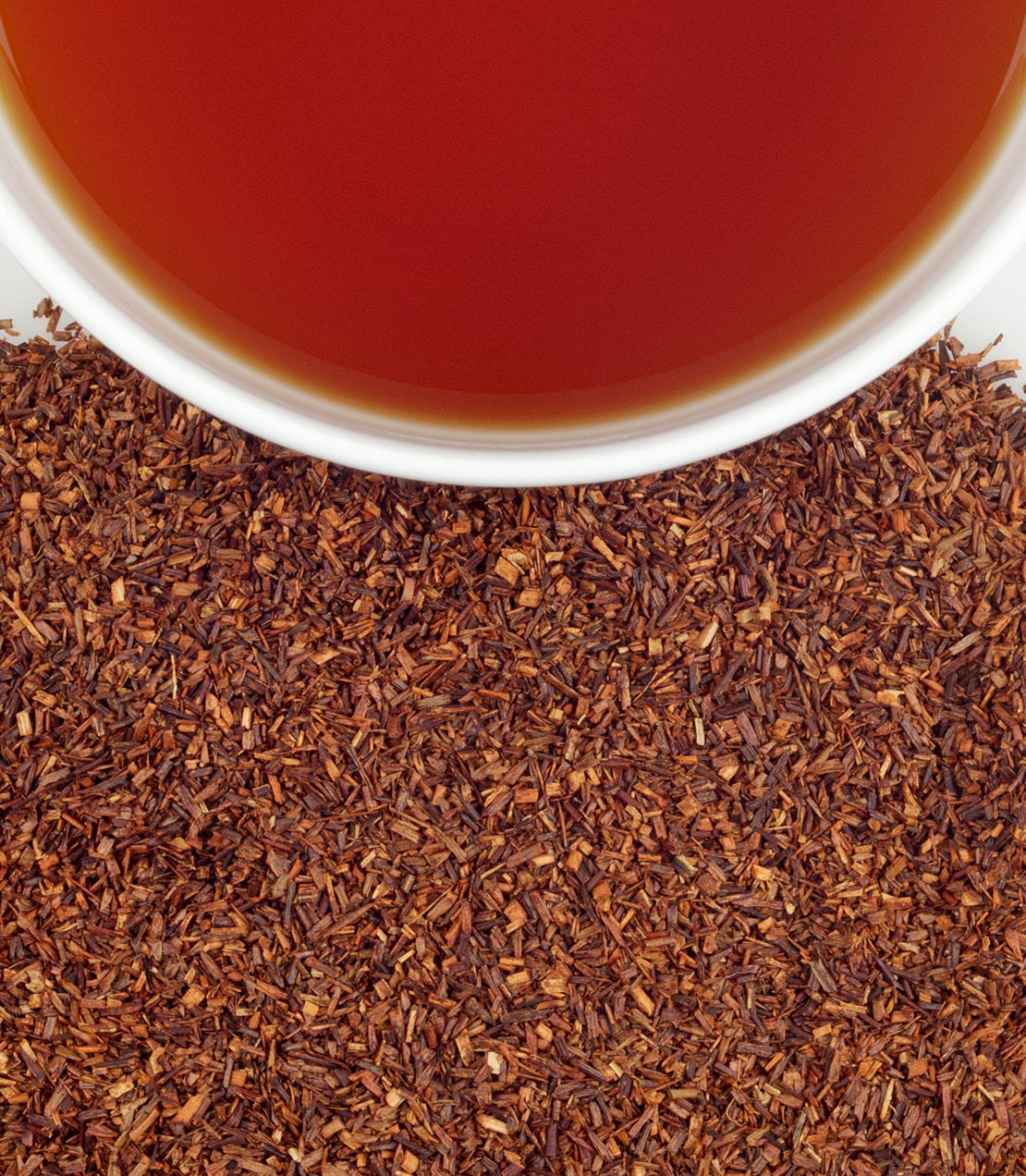 Organic Rooibos tea sachets with loose rooibos leaves and a cup of brewed tea, showcasing rich color and texture.