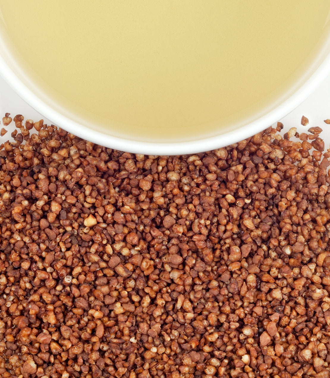 Soba roasted buckwheat grains scattered beside a bowl of light-colored liquid.