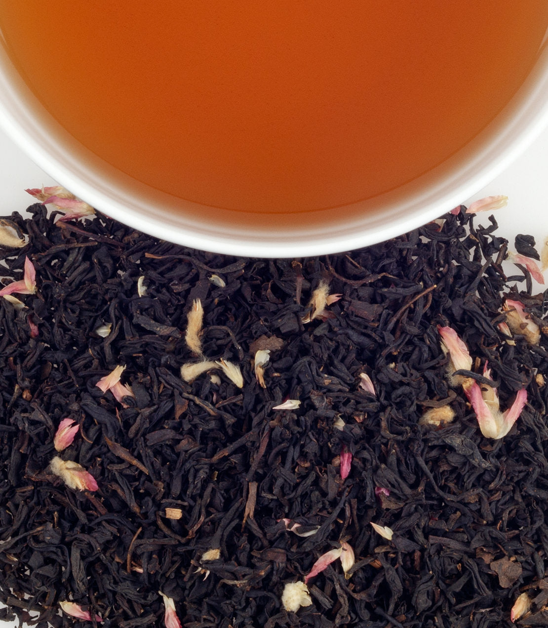 SoHo Blend tea sachets in a tin, with loose black tea and rose petals beside a cup of brewed tea.