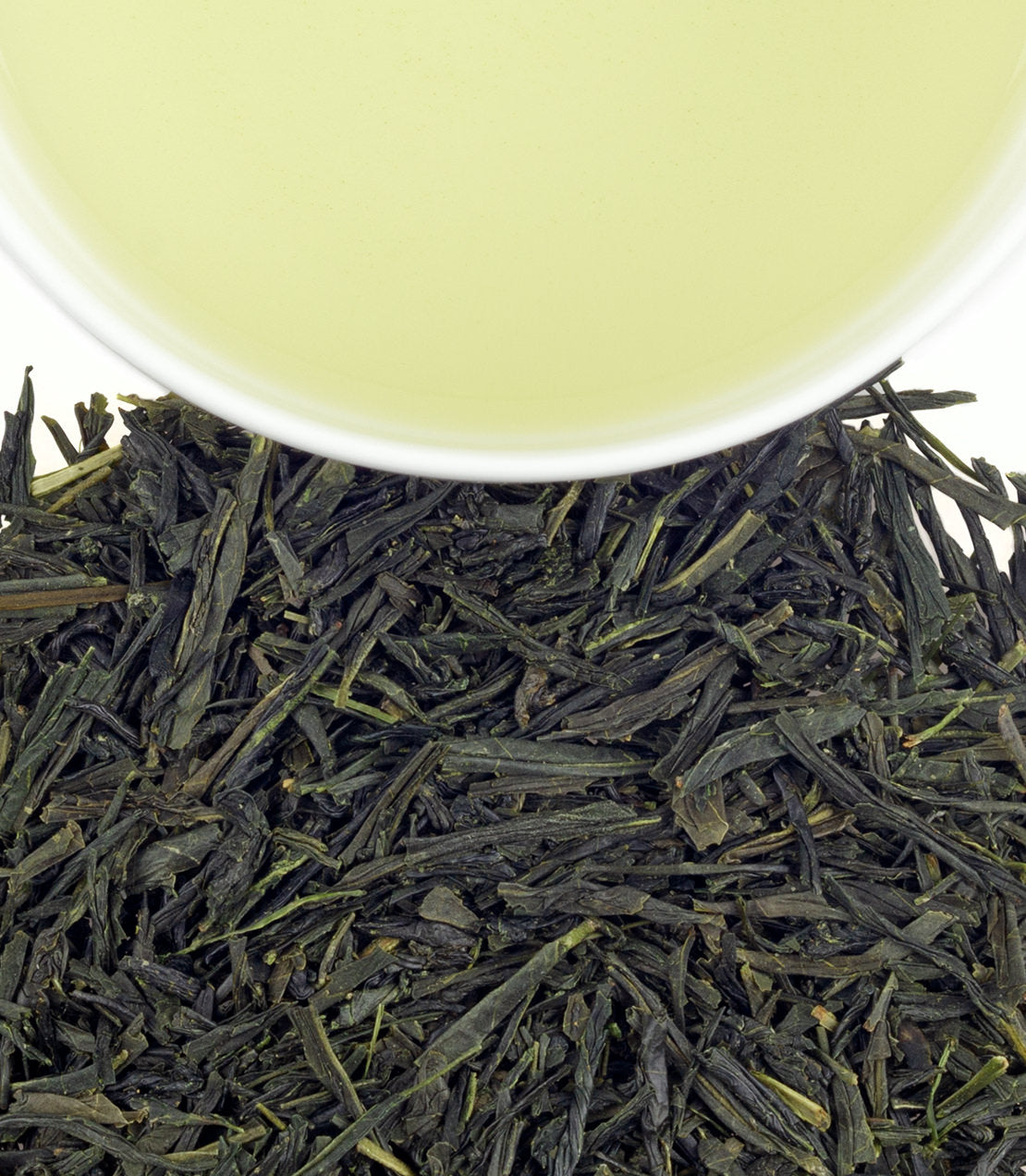 Close-up of Yanagi Premium Green tea leaves with a cup of brewed green tea above, showcasing vibrant colors.