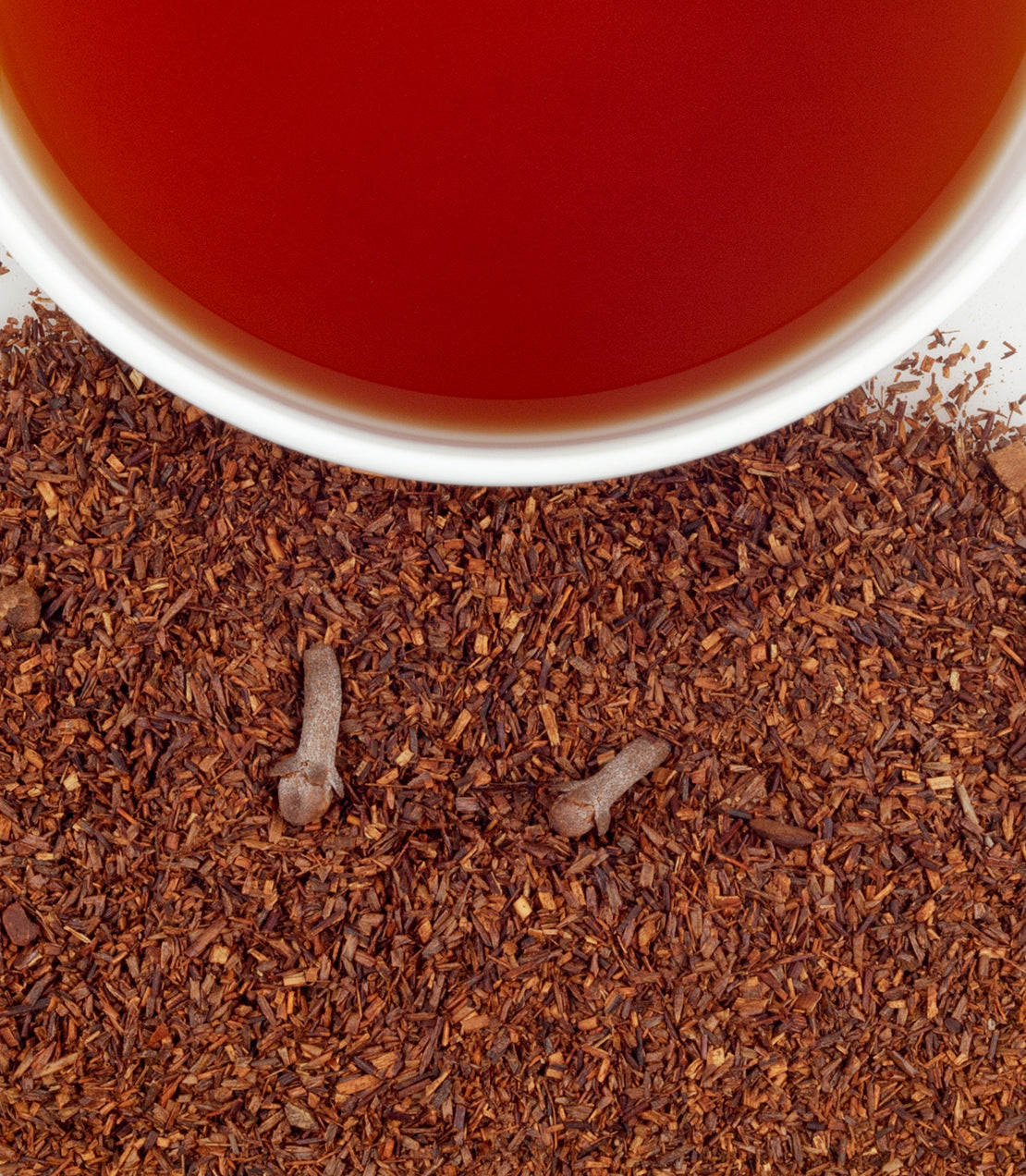 A close-up of pumpkin spice tea with loose tea leaves and whole cloves, showcasing warm autumn colors.